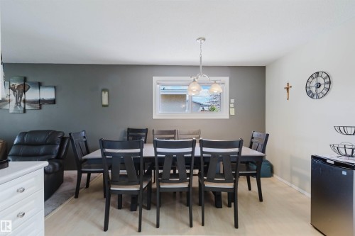 Dining area featuring a contemporary chandelier, light wood-finish flooring, and a window with white trim - 10519 36A Avenue, Edmonton, AB - Indoor Photo Showing Dining Room