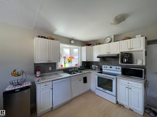 Kitchen featuring white cabinetry, light countertops, and a bay window - 10519 36A Avenue, Edmonton, AB - Indoor Photo Showing Kitchen With Double Sink