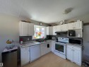 Kitchen featuring white cabinetry, light countertops, and a bay window - 10519 36A Avenue, Edmonton, AB  - Indoor Photo Showing Kitchen With Double Sink 
