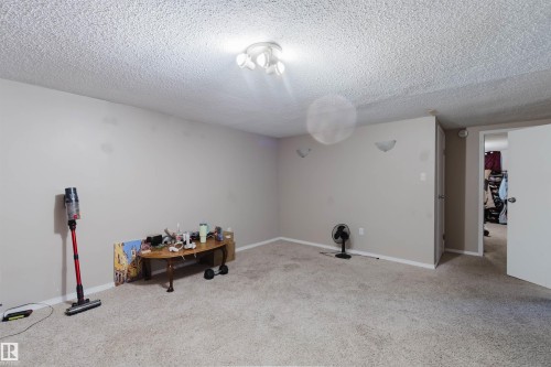 Carpeted room featuring neutral wall tones and a textured ceiling - 10519 36A Avenue, Edmonton, AB - Indoor