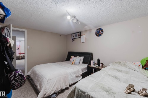 Spacious room featuring neutral paint, textured ceiling, and a flush-mount ceiling fixture with multiple lights - 10519 36A Avenue, Edmonton, AB - Indoor Photo Showing Bedroom