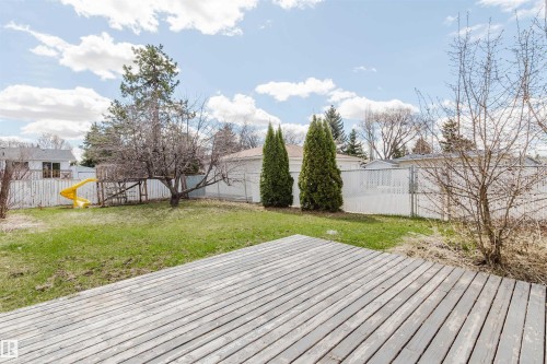 Expansive backyard featuring a wood deck, green lawn, and mature trees - 10519 36A Avenue, Edmonton, AB - Outdoor