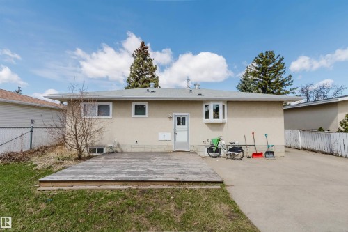 Exterior featuring a wood deck, concrete driveway, bay window, multiple windows, and a rear entry door - 10519 36A Avenue, Edmonton, AB - Outdoor