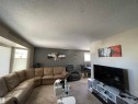 Open-concept living space featuring neutral-toned walls, carpet flooring, and a large bay window with horizontal blinds - 10519 36A Avenue, Edmonton, AB  - Indoor Photo Showing Living Room 