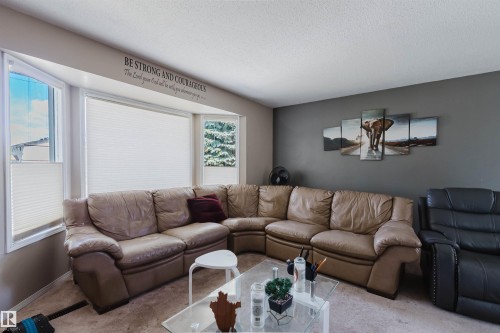 Bright living area with a large bay window, neutral-toned walls, and carpet flooring - 10519 36A Avenue, Edmonton, AB - Indoor Photo Showing Living Room