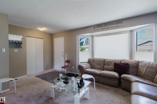 Living area featuring a bay window, wall-to-wall carpeting, and a built-in closet with bifold doors - 10519 36A Avenue, Edmonton, AB - Indoor Photo Showing Living Room