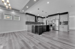 Open-concept kitchen featuring an island with integrated wine storage, stainless steel appliances, a mosaic tile backsplash, wood-finish flooring, and recessed ceiling lighting - 