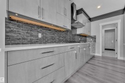 Contemporary kitchen featuring light wood-finish cabinetry, solid surface countertops, and a dark tile backsplash - 