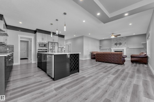 Open-concept living space featuring a central kitchen island with integrated wine storage, stainless steel appliances, and pendant lighting - 4403 Triomphe Gate, Beaumont, AB - Indoor Photo Showing Kitchen With Upgraded Kitchen