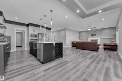 Open-concept living space featuring a central kitchen island with integrated wine storage, stainless steel appliances, and pendant lighting - 