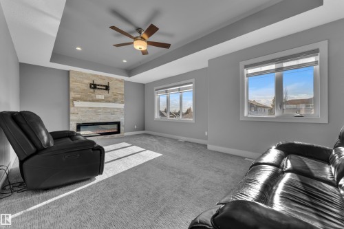 Interior room featuring a tray ceiling with a ceiling fan and recessed lighting - 4403 Triomphe Gate, Beaumont, AB - Indoor Photo Showing Living Room With Fireplace