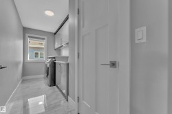 Dedicated laundry room featuring large format tile flooring, a window providing natural light, built-in cabinetry with under-cabinet lighting, and a countertop workspace - 