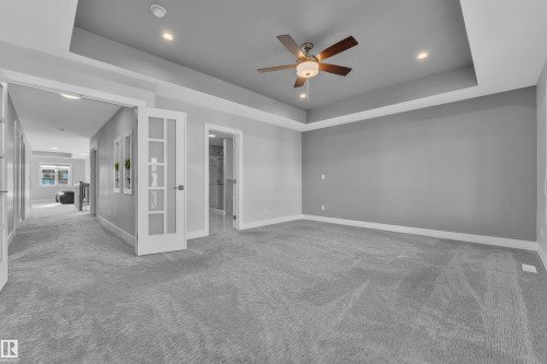 Spacious room featuring tray ceiling with recessed lighting and ceiling fan, plush carpet, and light gray wall paint - 4403 Triomphe Gate, Beaumont, AB - Indoor Photo Showing Other Room