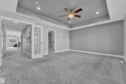 Spacious room featuring tray ceiling with recessed lighting and ceiling fan, plush carpet, and light gray wall paint - 