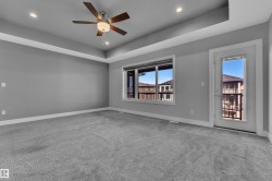 Spacious room featuring tray ceilings, recessed lighting, and soft gray carpeting - 