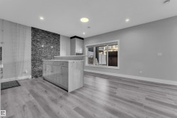 Open-concept room featuring light wood-finish flooring, a stone-accented wall, and recessed lighting - 