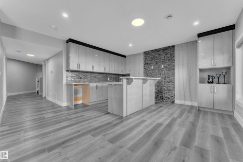 Open-concept living space featuring wood-finish flooring, recessed lighting, and a kitchen area with light-toned cabinetry - 4403 Triomphe Gate, Beaumont, AB - Indoor Photo Showing Other Room
