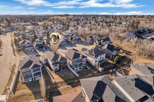 Aerial overview of a residential area featuring multiple detached properties with dark asphalt shingle roofs - 4403 Triomphe Gate, Beaumont, AB - Outdoor With View