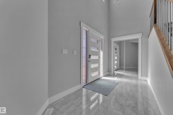 Entryway featuring a contemporary front door with frosted glass panels, large format tile flooring, a mirrored closet, and a staircase with wood treads and metal balusters - 