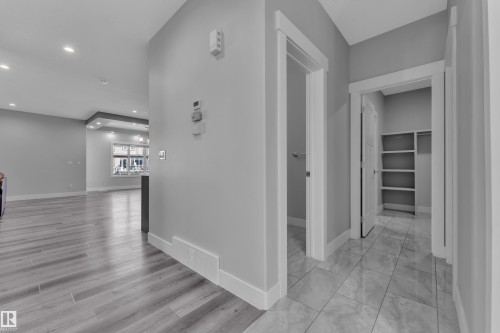 Foyer with tiled flooring and white baseboards, offering access to an interior space with built-in shelving and a separate doorway - 4403 Triomphe Gate, Beaumont, AB - Indoor Photo Showing Other Room