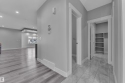 Foyer with tiled flooring and white baseboards, offering access to an interior space with built-in shelving and a separate doorway - 