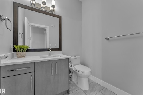 Bathroom vanity featuring a light-toned countertop, integrated sink, and gray cabinetry with brushed nickel hardware - 4403 Triomphe Gate, Beaumont, AB - Indoor Photo Showing Bathroom