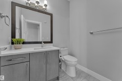 Bathroom vanity featuring a light-toned countertop, integrated sink, and gray cabinetry with brushed nickel hardware - 