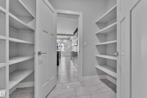 Walk-in pantry featuring built-in shelving, panel doors, and tile flooring - 4403 Triomphe Gate, Beaumont, AB - Indoor With Storage