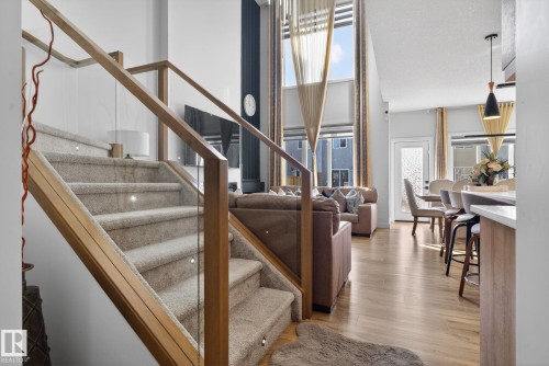 Staircase with wood and glass railing, integrated stair lighting, and light-colored carpeting - 3605 42 Avenue, Beaumont, AB - Indoor Photo Showing Other Room