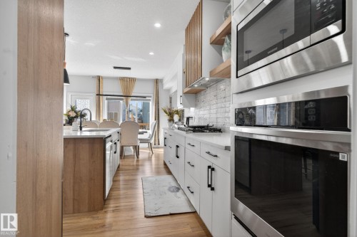 Modern kitchen featuring white cabinetry with matte black hardware, stainless steel appliances, a gas cooktop, and a white subway tile backsplash - 3605 42 Avenue, Beaumont, AB - Indoor Photo Showing Kitchen With Upgraded Kitchen