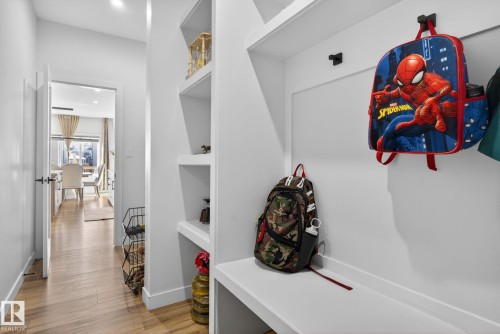 Hallway featuring built-in shelving, integrated coat hooks, wood-finish flooring, recessed lighting, and a white interior door with black hardware - 3605 42 Avenue, Beaumont, AB - Indoor Photo Showing Other Room