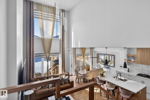 Open-concept living space featuring high ceilings, tall windows with transom details, and wood-finish flooring - 3605 42 Avenue, Beaumont, AB - Indoor
