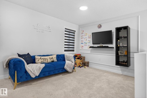 Carpeted room featuring a ceiling-mounted light fixture and a window with horizontal blinds - 3605 42 Avenue, Beaumont, AB - Indoor