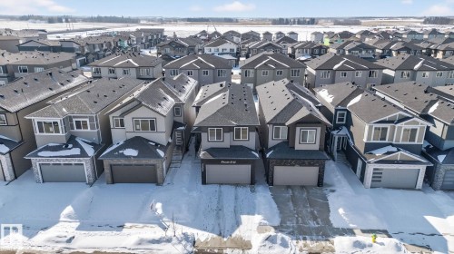 Contemporary residential streetscape featuring numerous two-story homes with attached garages, dark shingle roofing, and light-toned siding - 3605 42 Avenue, Beaumont, AB -  With Facade