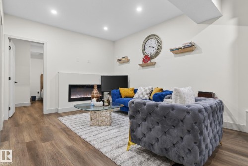 Living area featuring wood-finish flooring, recessed lighting, and a built-in electric fireplace - 3605 42 Avenue, Beaumont, AB - Indoor Photo Showing Other Room With Fireplace