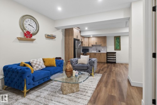 Open-concept living area featuring wood-finish flooring, a contemporary kitchenette with stainless steel appliances, recessed lighting, and a white color palette - 3605 42 Avenue, Beaumont, AB - Indoor Photo Showing Living Room