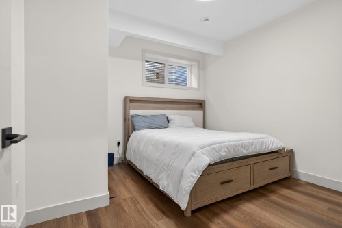 Bright room featuring wood-finish flooring, crisp white walls, a recessed light fixture, and a window with blinds - 3605 42 Avenue, Beaumont, AB - Indoor Photo Showing Bedroom