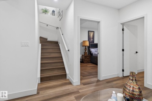 Interior staircase with wood-finish treads and white risers, featuring a white handrail with black accents - 3605 42 Avenue, Beaumont, AB - Indoor Photo Showing Other Room