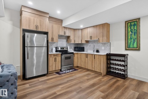 Contemporary kitchen featuring wood-finish cabinetry, stainless steel appliances, white countertops, and a full-height marble-look backsplash - 3605 42 Avenue, Beaumont, AB - Indoor Photo Showing Kitchen With Stainless Steel Kitchen