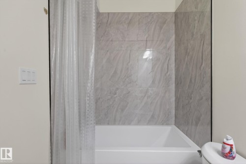 Bathtub with light gray marble-look tile surround and white walls - 3605 42 Avenue, Beaumont, AB - Indoor Photo Showing Bathroom