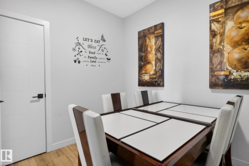 Dining area featuring light-colored walls, wood-finish flooring, and a contemporary white paneled door with black hardware - 3605 42 Avenue, Beaumont, AB - Indoor Photo Showing Other Room