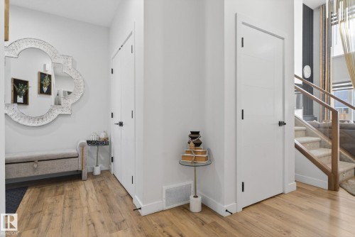 Entryway with wood-finish flooring, white paneled doors, and contemporary black door hardware - 3605 42 Avenue, Beaumont, AB - Indoor Photo Showing Other Room