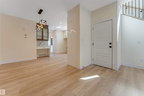 Light wood-finish flooring throughout, complemented by a modern geometric pendant light fixture - 10323 79 Street, Edmonton, AB - Indoor Photo Showing Other Room
