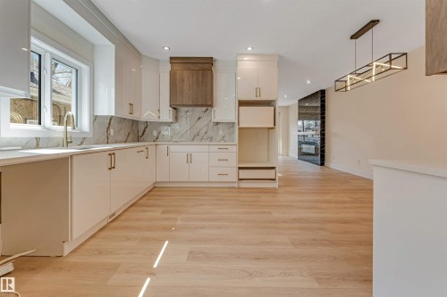 Expansive kitchen featuring white glossy cabinetry, light wood-finish flooring, and a large window above the sink - 10323 79 Street, Edmonton, AB - Indoor Photo Showing Kitchen With Upgraded Kitchen