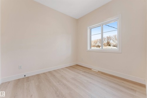 Main floor Bedroom Neutral wall color with crisp white baseboards and wood-finish flooring - 10323 79 Street, Edmonton, AB - Indoor Photo Showing Other Room