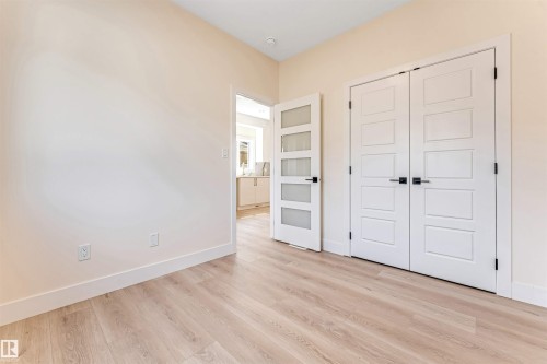 Light wood-finish flooring with white baseboards and neutral wall tones - 10323 79 Street, Edmonton, AB - Indoor Photo Showing Other Room