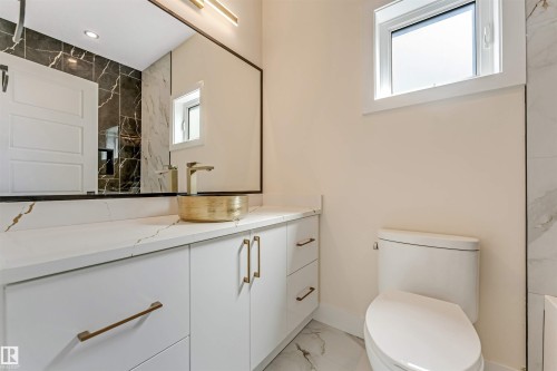 Main Floor Bathroom vanity featuring a vessel sink with a gold-tone faucet, white cabinetry with gold-tone hardware, and a white countertop - 10323 79 Street, Edmonton, AB - Indoor Photo Showing Bathroom
