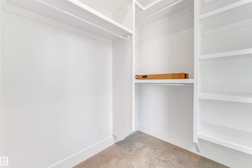 Custom closet system featuring white shelving, hanging rods, and a neutral carpeted floor - 10323 79 Street, Edmonton, AB - Indoor Photo Showing Other Room