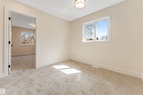 Carpeted room with neutral-toned walls, white trim, and a large window - 10323 79 Street, Edmonton, AB - Indoor Photo Showing Other Room