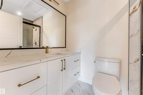 Contemporary bathroom featuring a white vanity with gold-tone hardware, a rectangular undermount sink, and a large mirror with a black frame - 10323 79 Street, Edmonton, AB - Indoor Photo Showing Bathroom